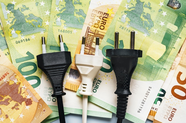 Plugue elétrico ao lado de notas de euro mostrando o problema da inflação financeira e a crise energética na Europa