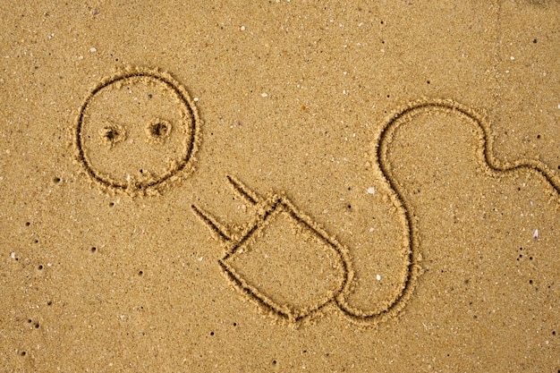 Plugue elétrico desenhado na areia