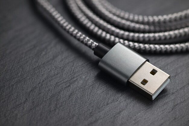 Plugue USB tipo A com cabo na rocha preta. Copie o espaço para o texto.