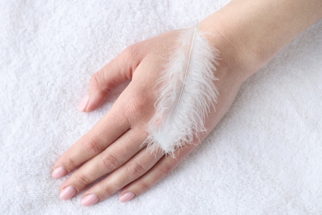 Pluma blanca suave en primer plano de mano de mujer