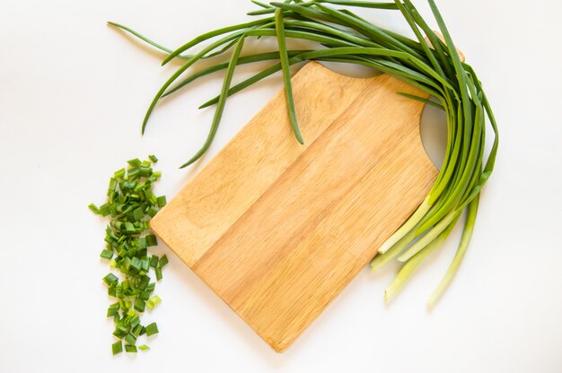 Pluma de cebolla verde plana y piezas en rodajas en el corte de tablero de madera aislado, concepto de comida orgánica, espacio de copia