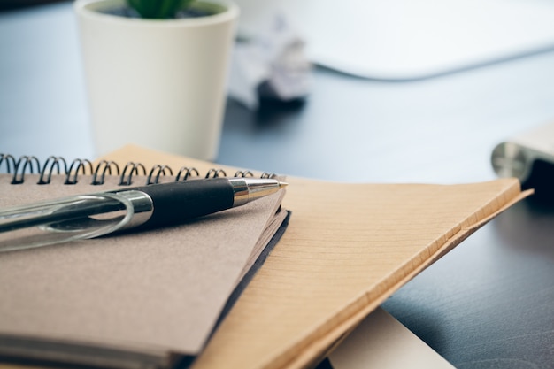 Pluma y cuaderno de cerca en un escritorio de oficina