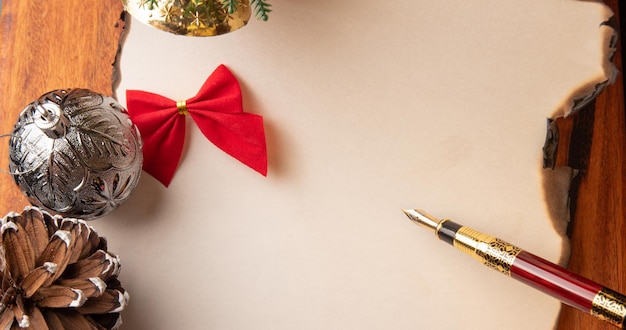 Pluma estilográfica una hermosa pluma estilográfica una hoja en blanco con bordes quemados y adornos navideños Enfoque selectivo