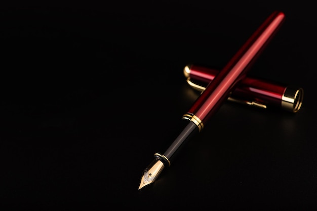 Pluma estilográfica hermosa pluma estilográfica roja y dorada posicionada sobre un fondo oscuro con enfoque selectivo