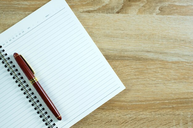 Pluma estilográfica o pluma de tinta con papel de cuaderno en la mesa