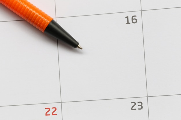 La pluma naranja se coloca en el calendario en el día 16 y tiene espacio de copia.