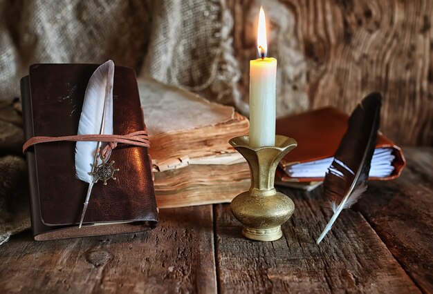 Foto pluma y novela de libro cerca de una vela.