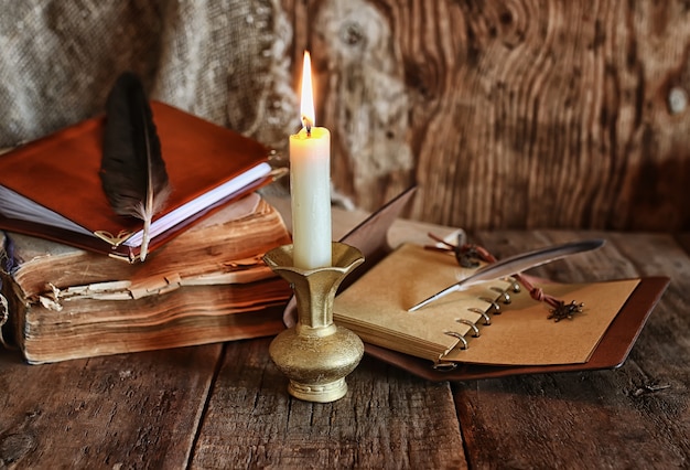 Pluma y novela de libro cerca de una vela.