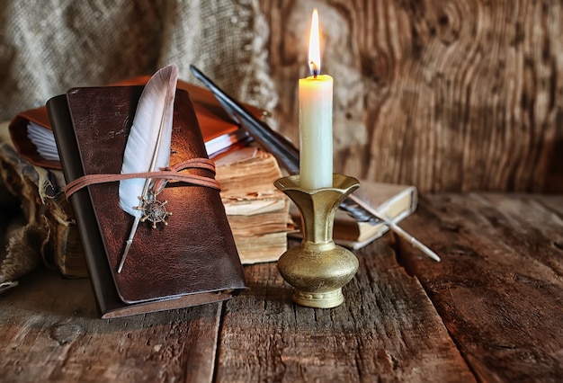 Pluma y novela de libro cerca de una vela.