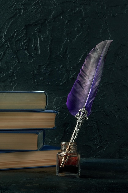 Pluma de pluma con un pozo de tinta vintage y una pila de libros viejos
