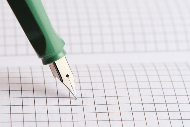La pluma pluma verde se encuentra en hojas blancas cuaderno a cuadros