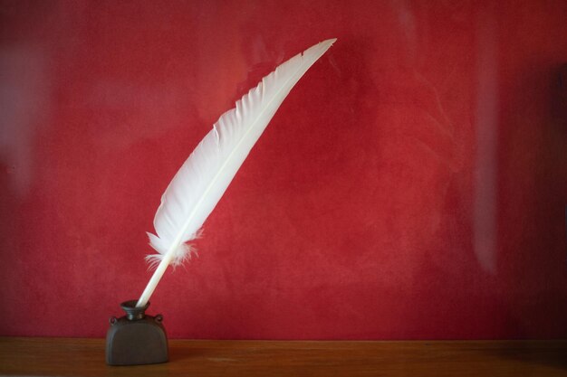 Pluma con tintero sobre un escritorio de madera Vintage estilo antiguo fotografía sepia fondo rojo