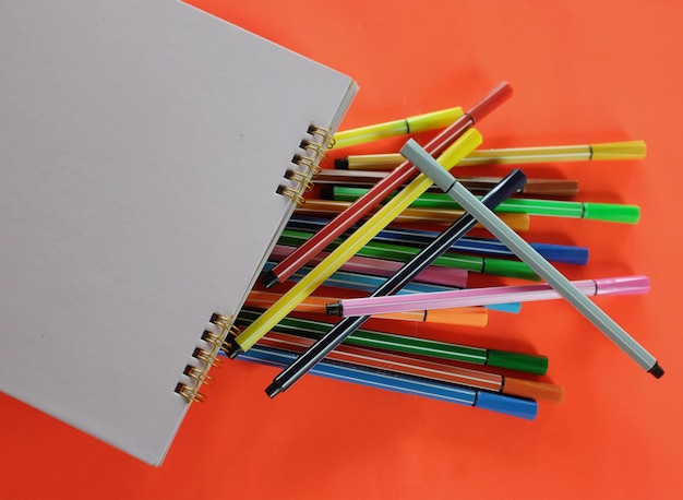 Foto plumas de colores papel blanco en la mesa de la oficina naranja