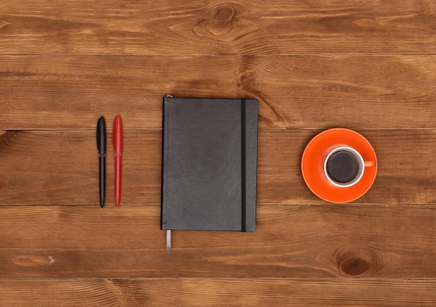 Plumas de diario y taza de café.