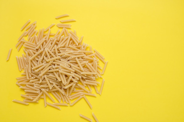 Plumas de pasta sobre fondo amarillo con espacio de copia