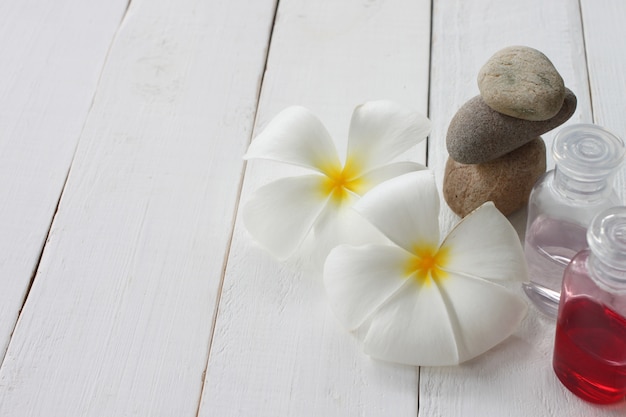 Foto plumeria- und gelflasche wird auf einen weißen holzboden gestellt.