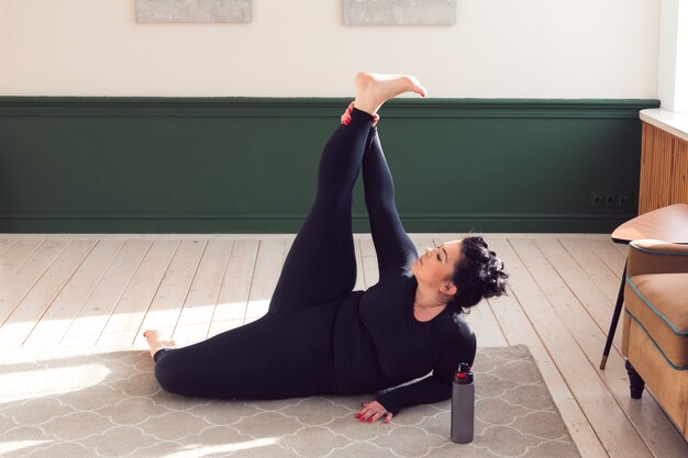 Plus Size Frau macht Pilates Yoga Stretching Übung zu Hause