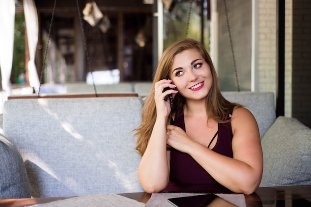 Plus size hermosa joven con tableta y teléfono en un restaurante.