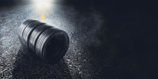 Pneu de carro em uma estrada pavimentada com fumaça e um farol de carro no fundo à noite espaço de cópia de banner panorâmico em fundo preto