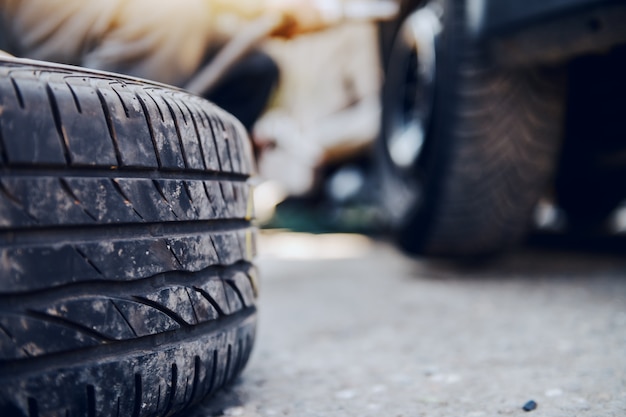 Pneu de mudança do auto mecânico ao agachar-se na oficina. Foco seletivo no pneu.