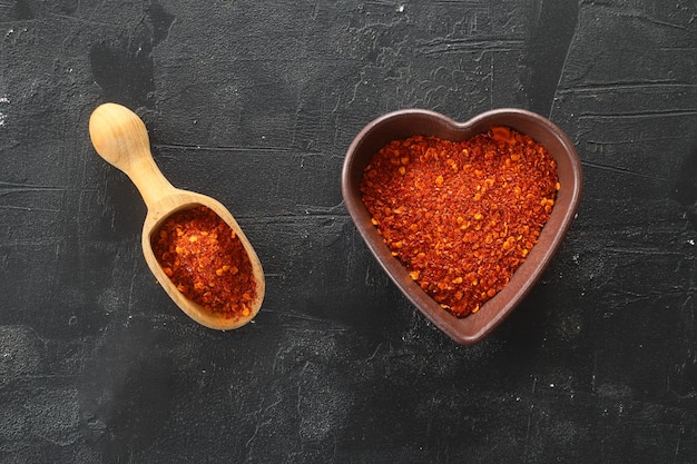 pó de pimenta malagueta vermelha em tigela em forma de coração na mesa de pedra preta Conceito de amor Vista superior