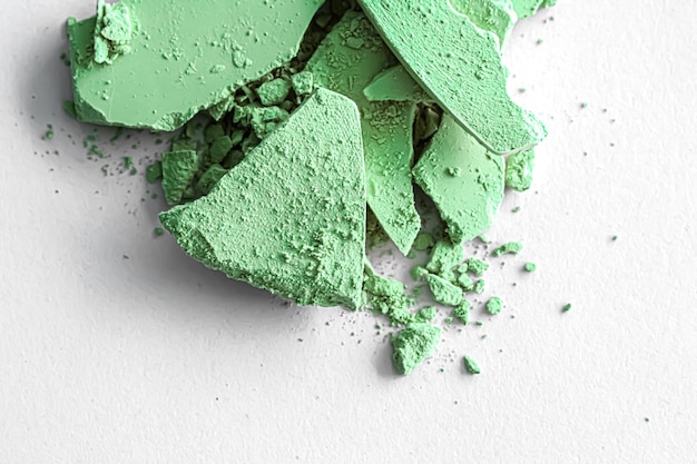 Pó de sombra verde como paleta de maquiagem isolada em fundo branco, cosméticos esmagados e textura de beleza
