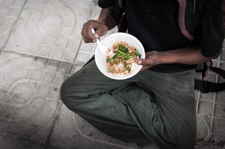 Pobre homem sem-teto com as mãos sujas, comendo comida no chão da rua
