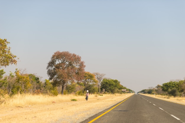 Pobre mujer caminando en la carretera en la franja rural de Caprivi, la región más poblada de Namibia, África.