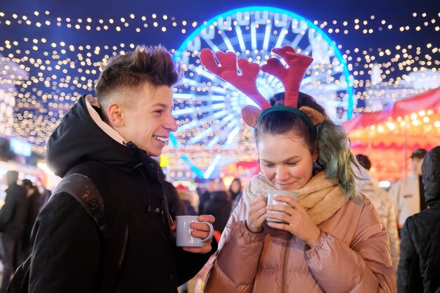 Época de Natal, feriados de ano novo. Jovens, casal de adolescentes se divertindo no mercado de Natal