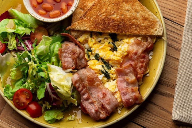 Pochierte Eier mit Gemüseschinken, Tomaten, roten Bohnen und Sauerteig-Toast auf Holzhintergrund isoliert Hausgemachtes Essen Leckeres Frühstück