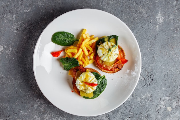 Pochierte Eier mit Pommes Frites und Speck auf Toast