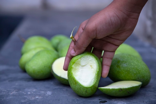 Un poco de mango verde crudo con una rebanada de mango en el piso de concreto