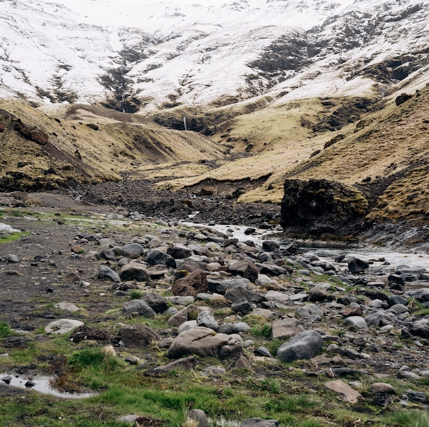 Poco profundo río de montaña fluye desde montañas nevadas hacia el desfiladero en una cascada