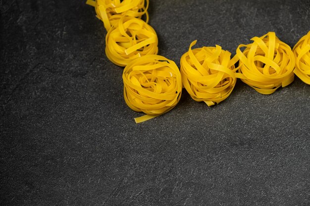 Foto pocos nidos de fettuccine caseros aislados en fondo oscuro