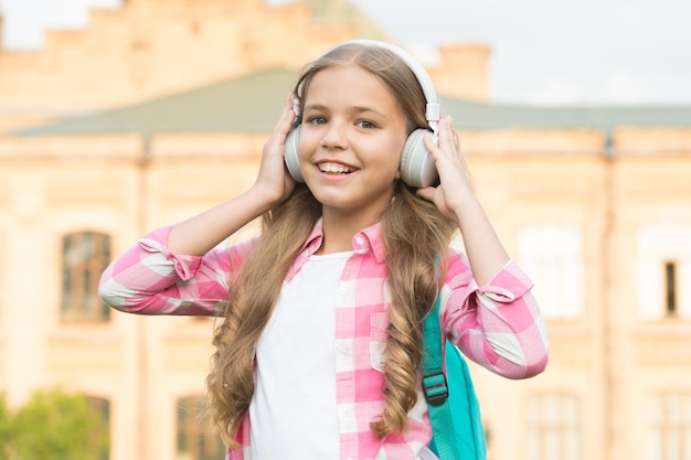 Podcast educacional Garota infantil gosta de música Tempo agradável Fones de ouvido de criança ouvem música Conceito de livro de áudio Estudando aulas de áudio Ouça música enquanto caminha Fones de ouvido de garota ouvindo música
