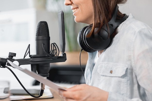 Podcaster crea contenido mujer europea graba podcast con micrófono y auriculares caucásicos