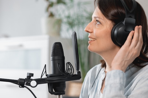 Podcaster cria podcast de registros de mulheres europeias com microfone e fones de ouvido caucasiana