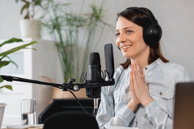 Podcaster cria podcast de registros de mulheres europeias com microfone e fones de ouvido caucasiana