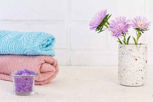 Pode com toalhas de sal marinho e flores de ásteres em um fundo branco