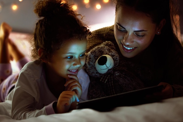 Podemos assistir meu programa Foto de uma mãe e filha usando um tablet digital antes de dormir