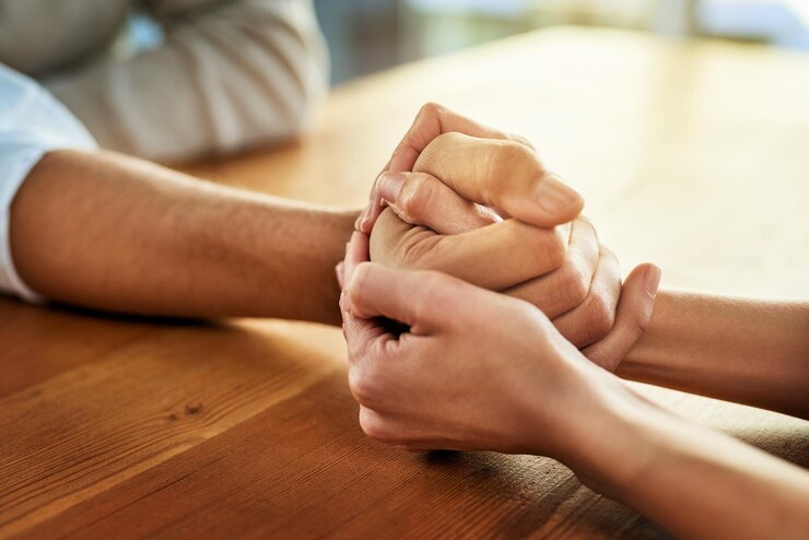 Foto podemos hacer esto juntos captura recortada de dos personas irreconocibles cogidas de la mano mientras están sentadas en una mesa en el interior durante el día