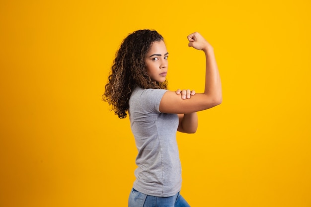 Podemos hacerlo. Puño de mujer de poder femenino. Mujer víctima de racismo. Abuso en el trabajo. El poder femenino. Empoderamiento femenino. La fuerza de la mujer. Fondo amarillo.