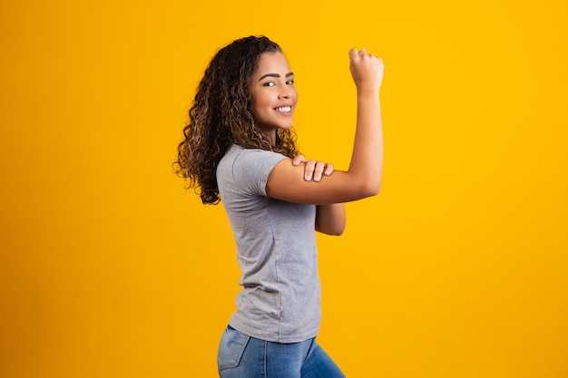 Podemos hacerlo. Puño de mujer de poder femenino. Mujer víctima de racismo. Abuso en el trabajo. El poder femenino. Empoderamiento femenino. La fuerza de la mujer. Fondo amarillo.