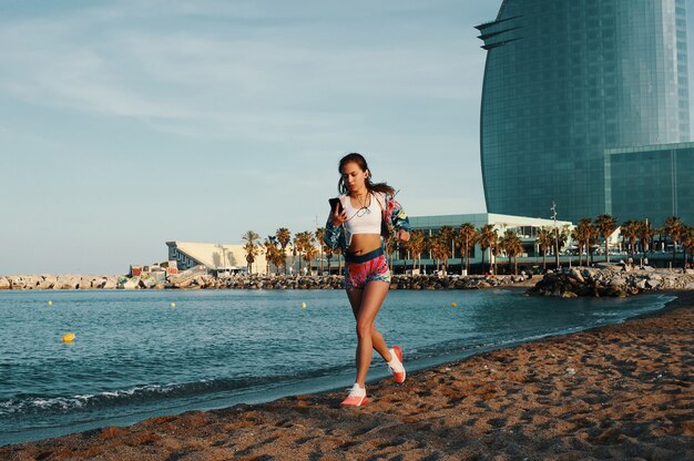 Poder y equilibrio. Longitud total de mujer joven atractiva en ropa deportiva para correr mientras hace ejercicio al aire libre