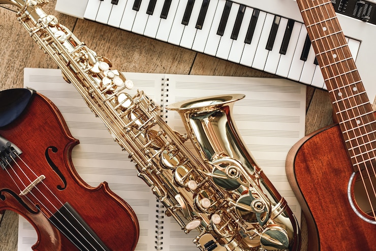 Foto poder de la música vista superior de instrumentos musicales sintetizador guitarra saxofón y violín acostado