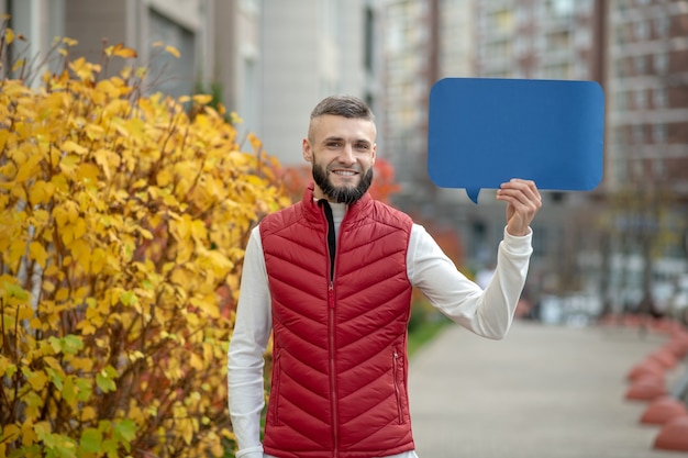 Poder de las palabras. Agradable joven mirándote mientras sostiene un cartel azul