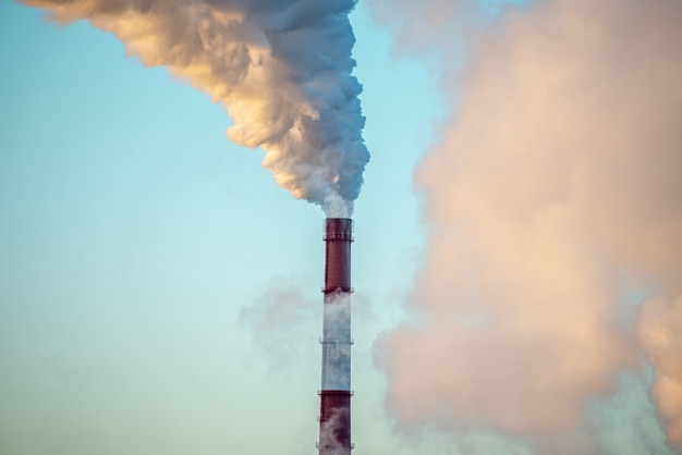 Poderosa chaminé de fábrica industrial está fumegando e emitindo dióxido de carbono no meio ambiente