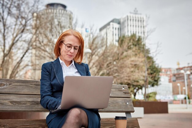 Poderosa empresaria haciéndose cargo afuera con su computadora portátil