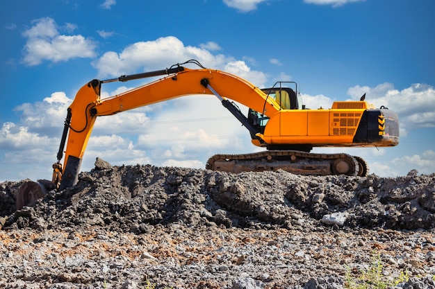 Una poderosa excavadora de oruga cava el suelo contra el cielo azul Movimientos de tierra con equipo pesado en el sitio de construcción