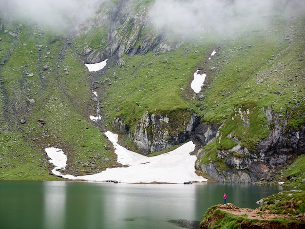 Poderosas montañas están cubiertas de niebla y el lago al pie